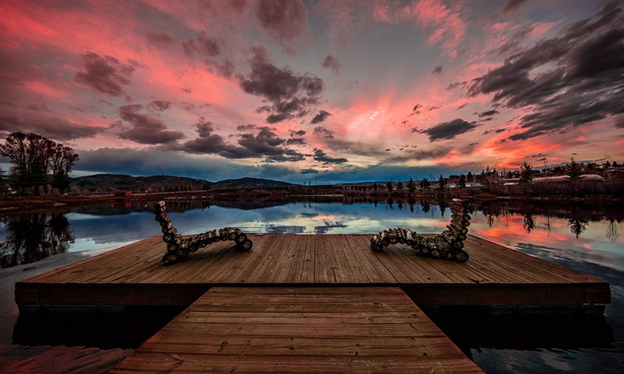 Two chairs on a dock overlooking a lake reflecting pink clouds — Eternal Peace